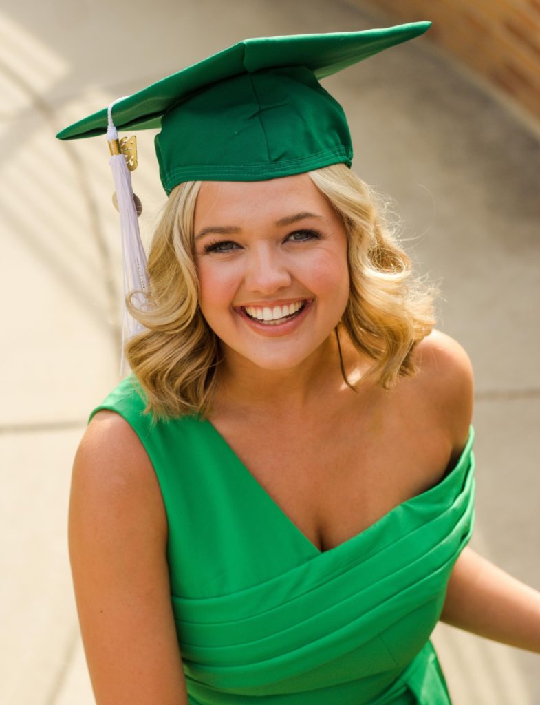 Close-up Portrait of Miss Michigan 2023, Maya Schuhknecht in a green dress and graduation cap for her Michigan State Graduation Photos. 
