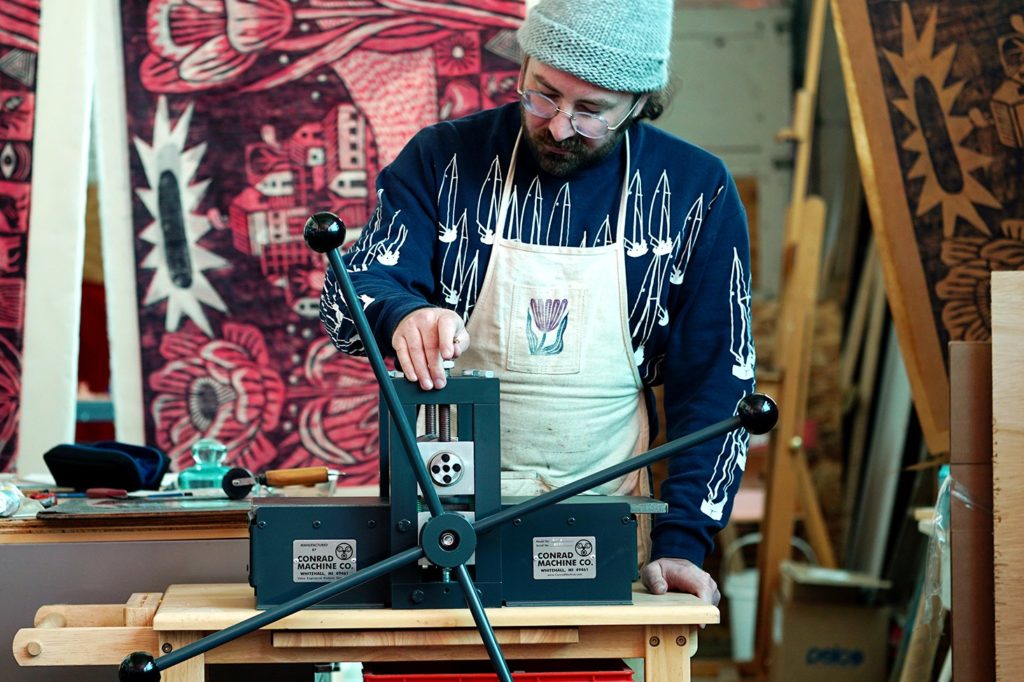 Trevor Grabill working at a machine in his art studio.