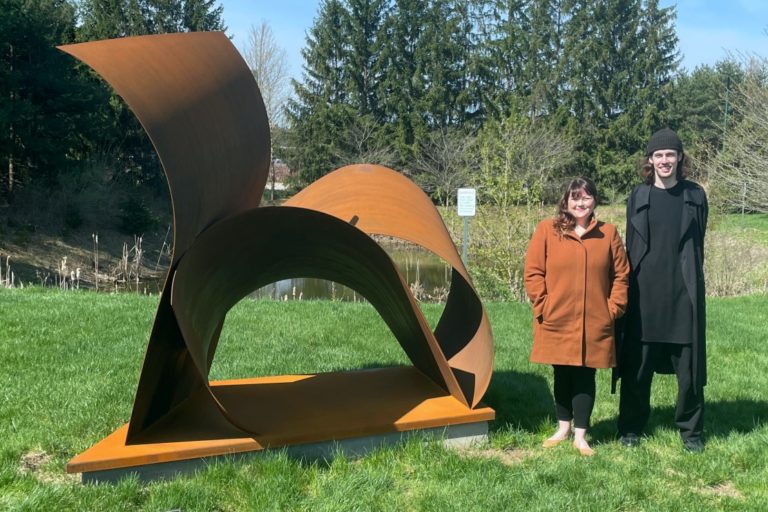 A picture of two people and a sculpture in a park.