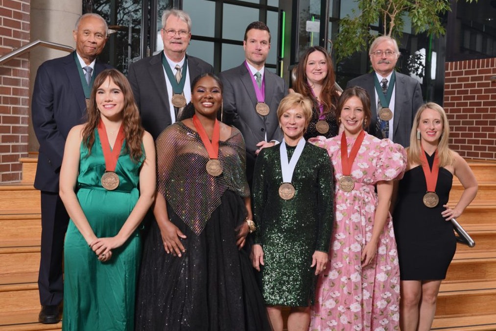 Group photo of 10 people all of whom have medallions around their neck. 