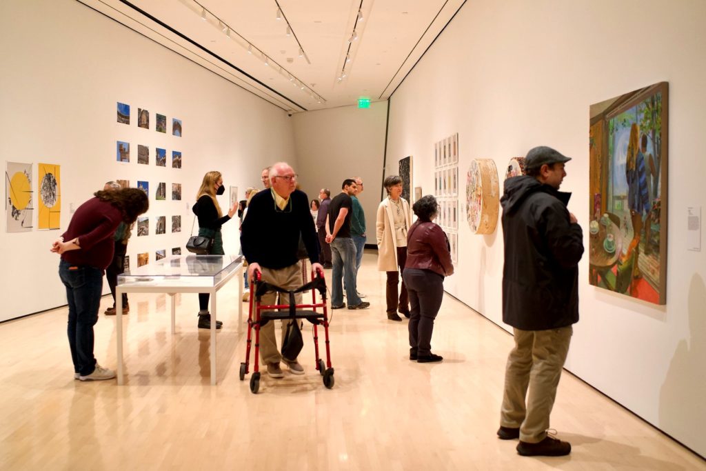Multiple people viewing artwork at a museum. 