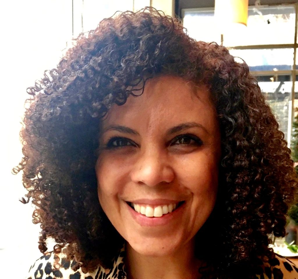 Headshot of a woman with short dark curly hair. 