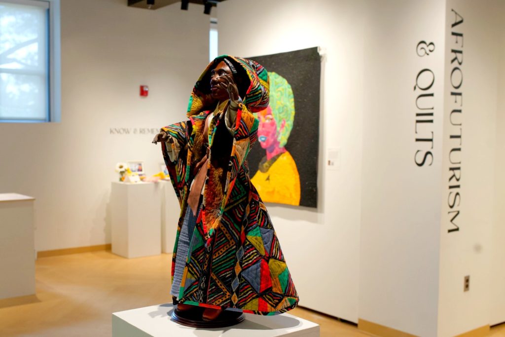Afrofuturism & Quilts Exhibit showing a figure of a Black person wearing a quilted colorful coat. 