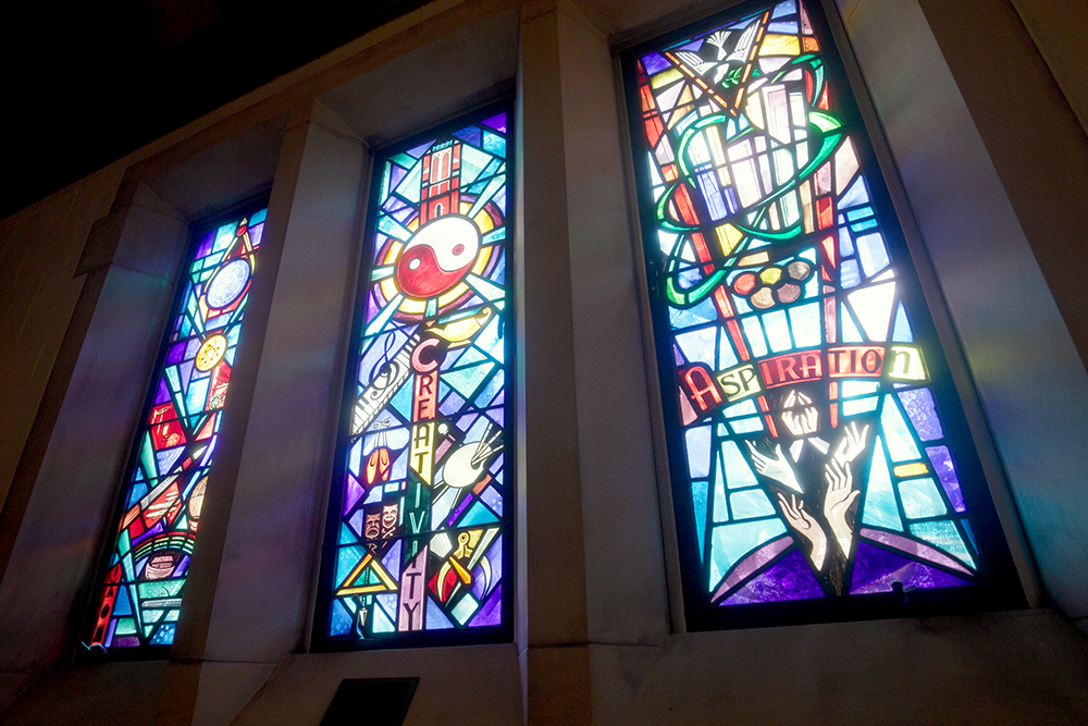 Brightly colored stained glass windows that say "creativity" and "aspiration"