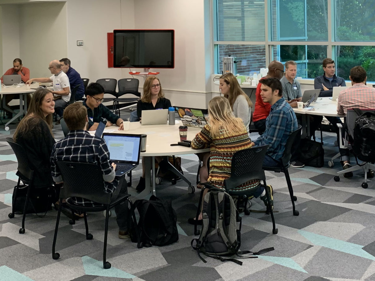 Digital humanities scholars engaged in group discussions at round tables