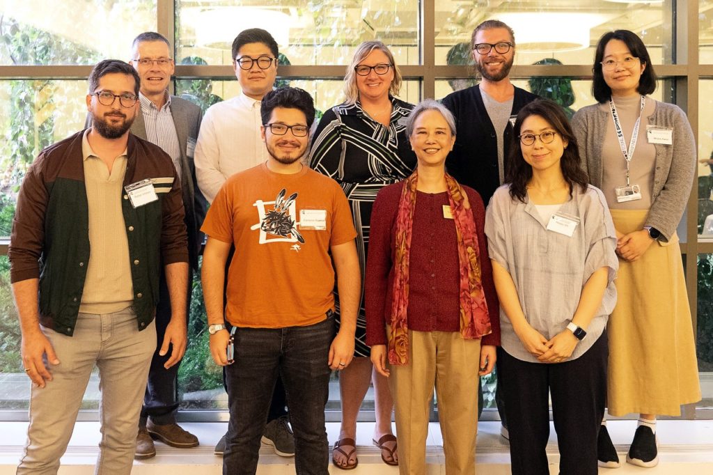 Group photo with nine people in two rows. the front row has four people and th back row has five people. 