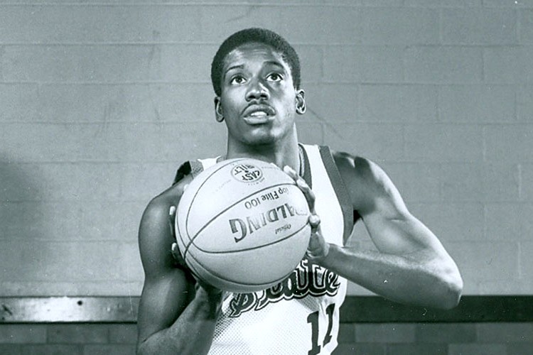 A black-and-white photo of a young basketball player in a Michigan State Spartans jersey, holding a basketball in preparation for a shot.