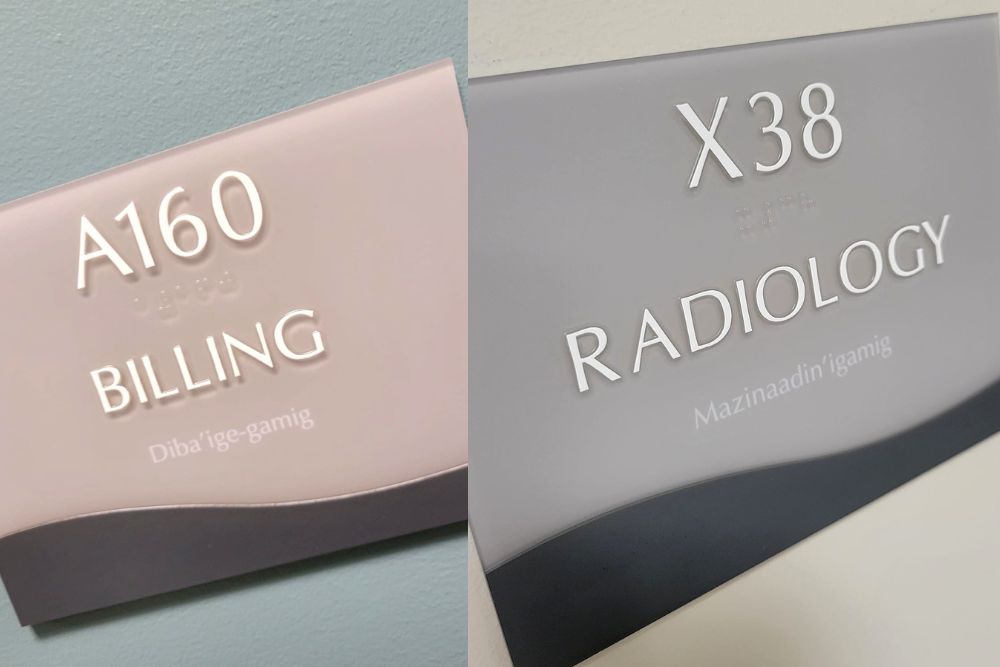 Two pictures of hospital signs: the one on the left is light pink and reads A160, Billing, Diba'ige-gamig; the sign on the right reads X38, Radiology, Mazinaadin'igamig. 