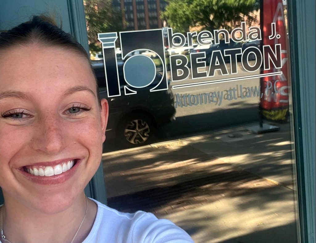 woman standing in front of glass door that says:" Brenda J. Beaton Attorney at Law, P.C.