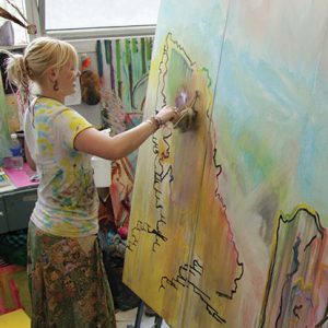 a woman with blonde hair painting a picture